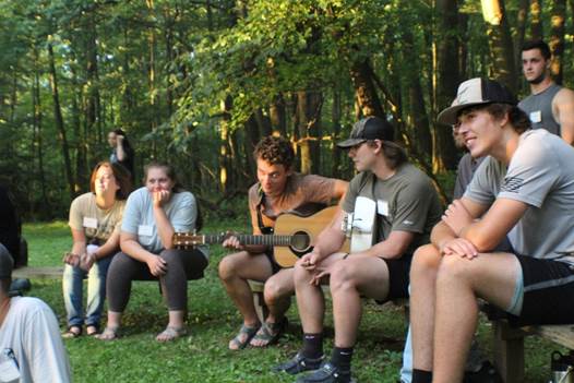 A group of people sitting on a bench playing guitar
