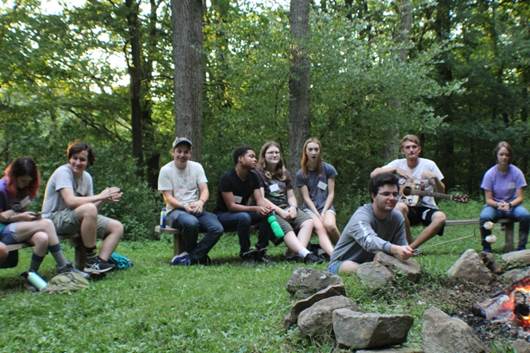 A group of people sitting on a bench in the woods